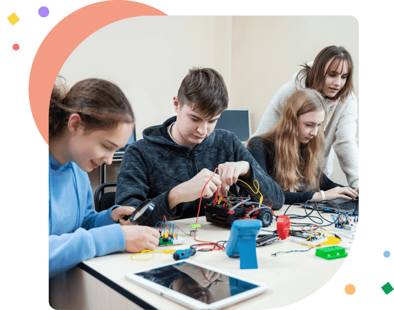 Diverse teenager pupils build robot vehicle learning at table at STEM engineering science education class.