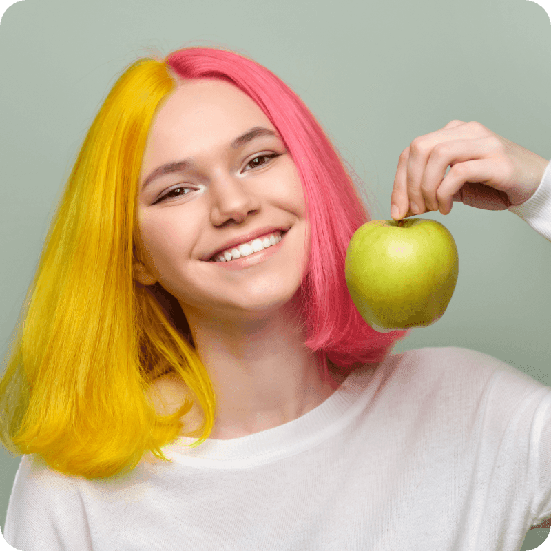 Head shot of beautiful smiling teenage girl with white smile with teeth, holding an apple
