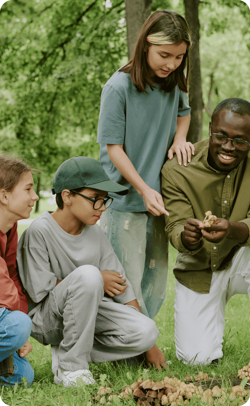 Diverse School Teacher Guiding Children Exploring Nature Outdoors in Park.