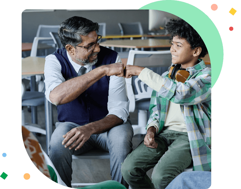 Cheerful mature school psychologist and African American teen boy doing fist bump during group therapy session